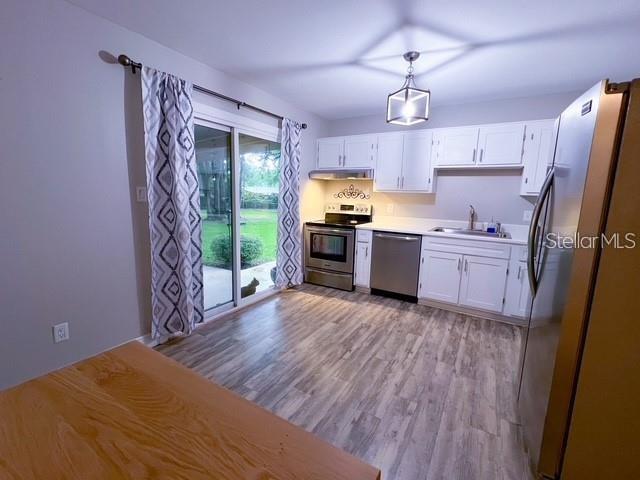 1928 Lawson Road Tallahassee, FL 32308 - Photo 9 of 20 a kitchen with stainless steel appliances a stove top oven a refrigerator a sink and dishwasher with wooden floor