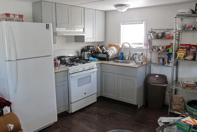a kitchen with sink a refrigerator and wooden floor