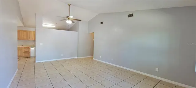 a view of an empty room with chandelier fan