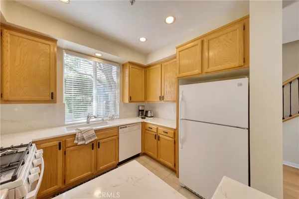 a kitchen with a sink a refrigerator a window and cabinets