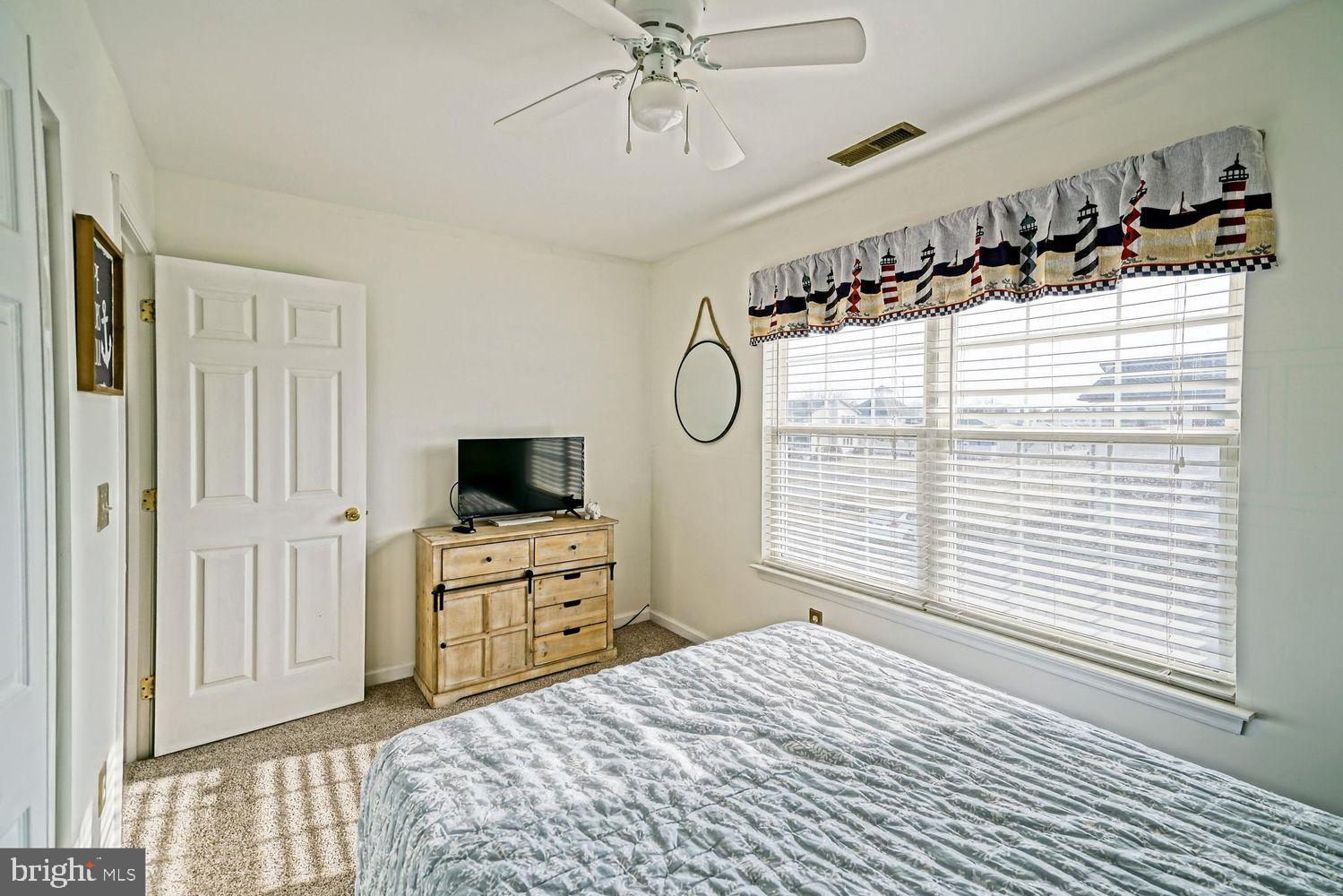 34531 Oakley Court, Unit 27 Lewes, DE 19958 - Photo 22 of 25 a bedroom with a bed and a flat tv screen on the dresser