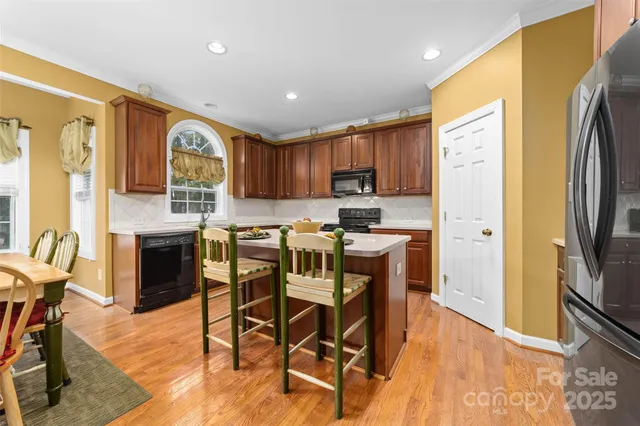 a kitchen with stainless steel appliances granite countertop a refrigerator a stove top oven a sink dishwasher and white cabinets with wooden floor