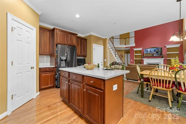 a kitchen with stainless steel appliances a stove a sink refrigerator and a dining table with wooden floor