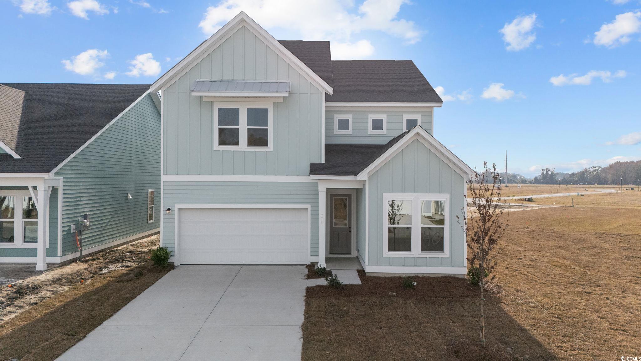 View of front facade featuring board and batten siding, concrete driveway, a shingled roof, and a garage