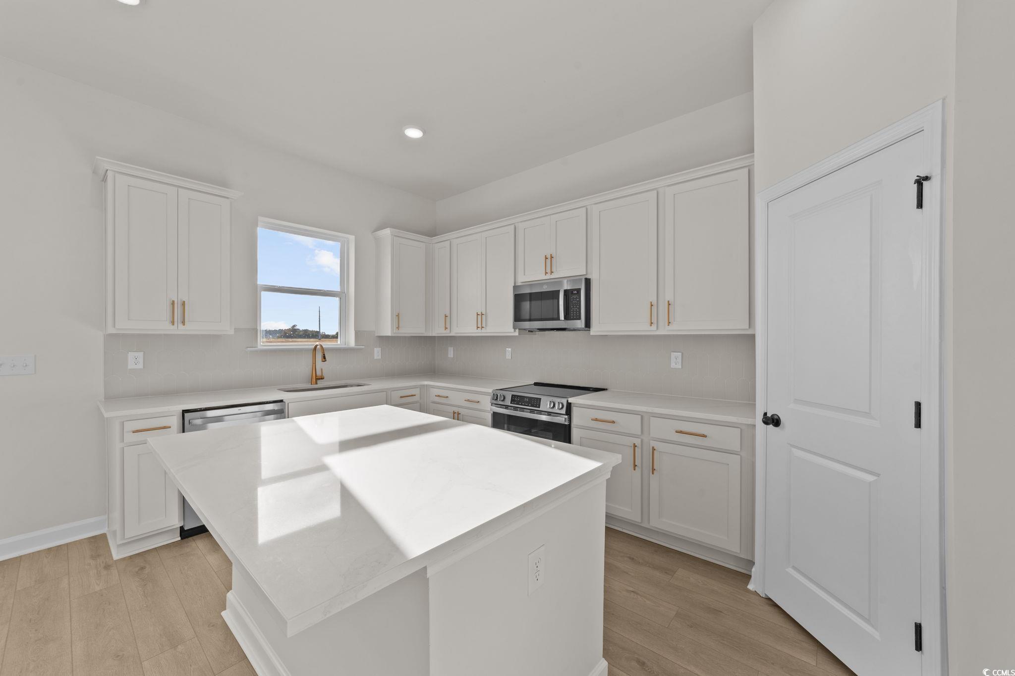 774 Ebb Tide Road Little River, SC 29566 - Photo 20 of 39 Kitchen featuring stainless steel appliances, white cabinets, a center island, light stone counters, and recessed lighting