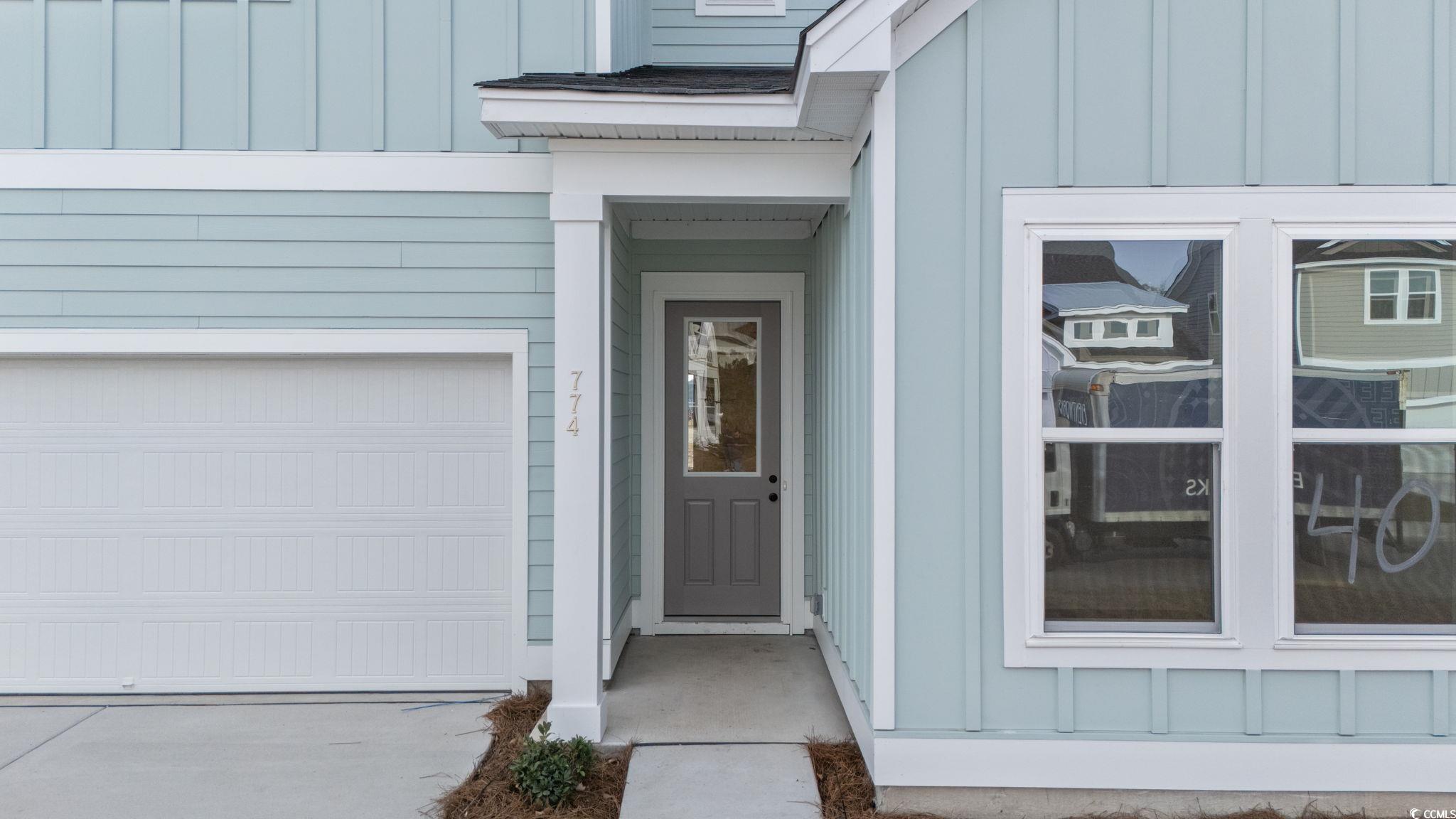 774 Ebb Tide Road Little River, SC 29566 - Photo 4 of 39 View of front facade featuring board and batten siding, concrete driveway, an attached garage, and a shingled roof
