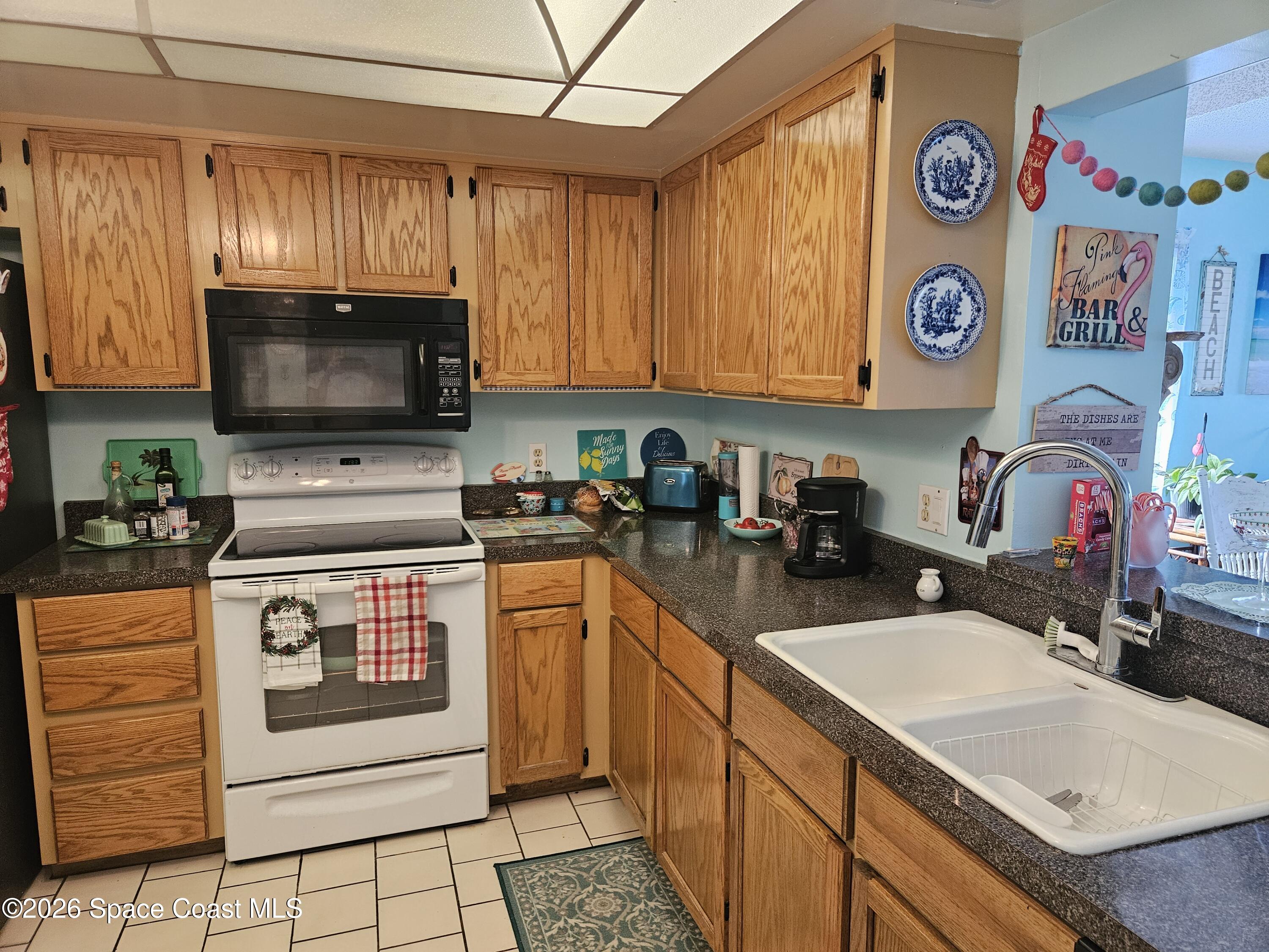 1750 Commodore Boulevard, Unit 2101 Cocoa Beach, FL 32931 - Photo 13 of 21 a kitchen with kitchen island granite countertop a sink a stove top oven a counter top space and cabinets