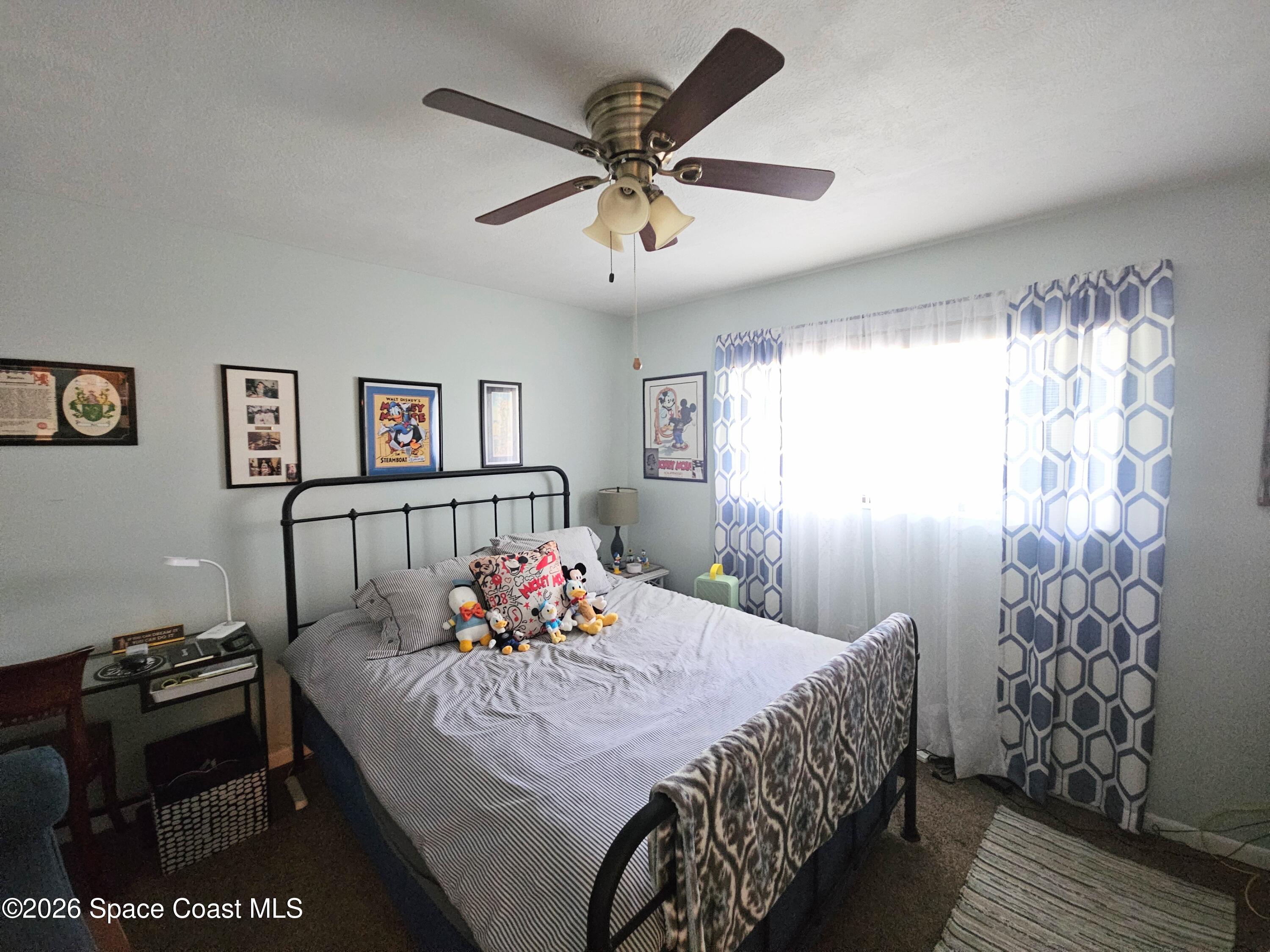1750 Commodore Boulevard, Unit 2101 Cocoa Beach, FL 32931 - Photo 15 of 21 a bedroom with a bed and a chandelier