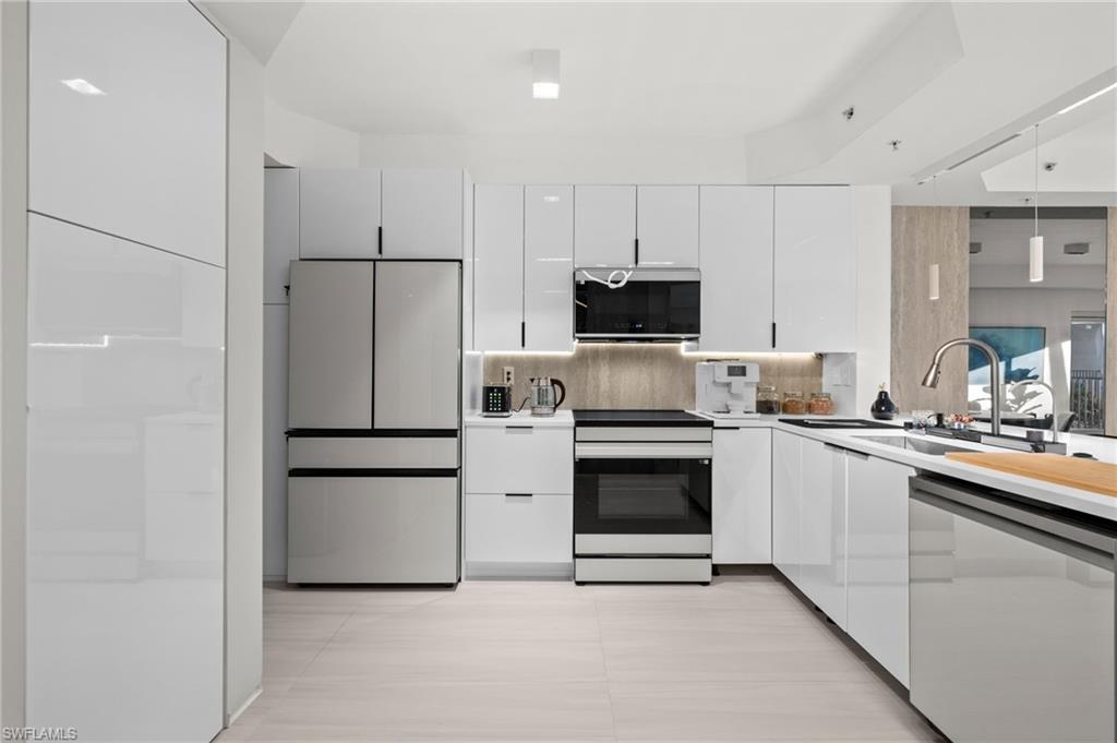 1100 Pine Ridge Road, Unit B103 Naples, FL 34108 - Photo 8 of 38 a kitchen with white cabinets and stainless steel appliances