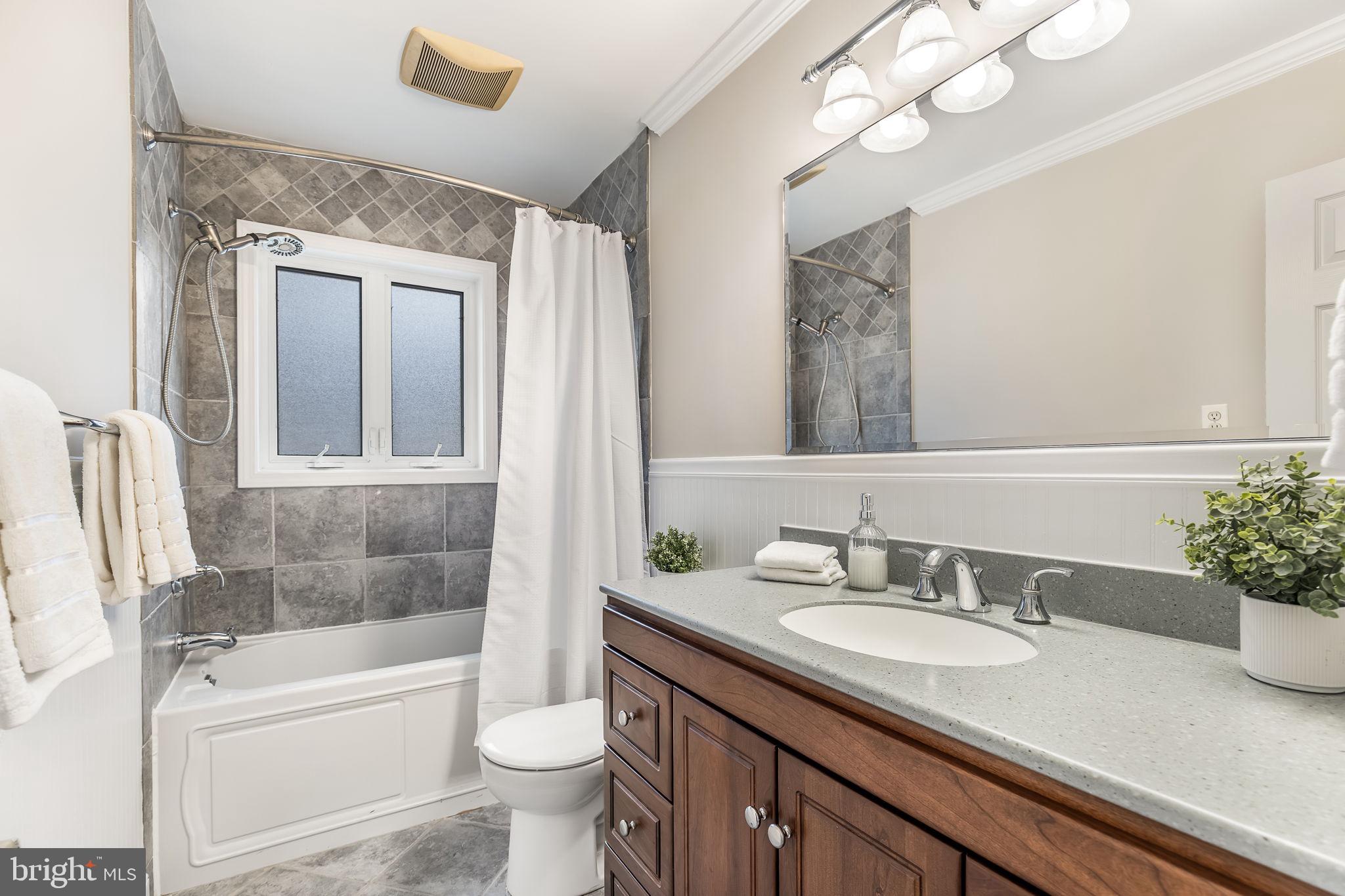 3103 Valley Lane Falls Church, VA 22044 - Photo 13 of 25 a bathroom with a granite countertop sink a toilet a mirror a vanity a bathtub and shower