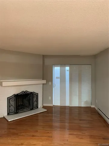 a view of empty room with wooden floor and fireplace