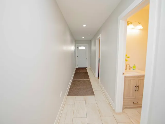 a view of a hallway with wooden floor and a bathroom
