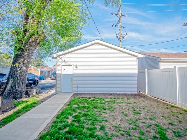 a view of a house with a small yard and a large tree