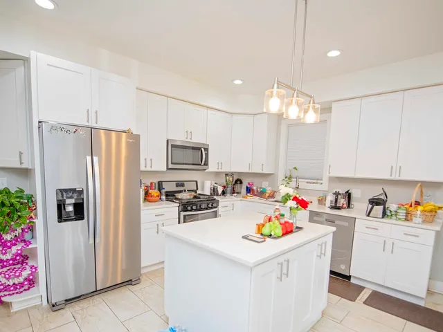a kitchen that has a lot of white cabinets and stainless steel appliances