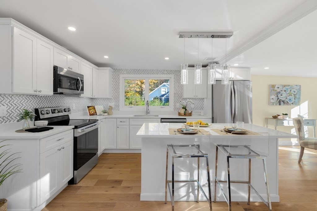 15 Red Acre Road Stow, MA 01775 - Photo 10 of 42 a kitchen with stainless steel appliances granite countertop a stove top oven a sink dishwasher a dining table and chairs with wooden floor