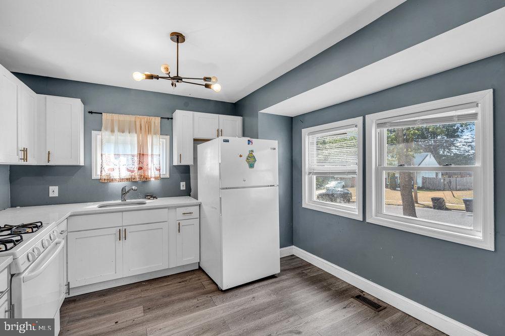 211 Chatham Drive Lindenwold, NJ 08021 - Photo 14 of 42 a kitchen with stainless steel appliances granite countertop a refrigerator a sink dishwasher a stove and white countertops with wooden floor