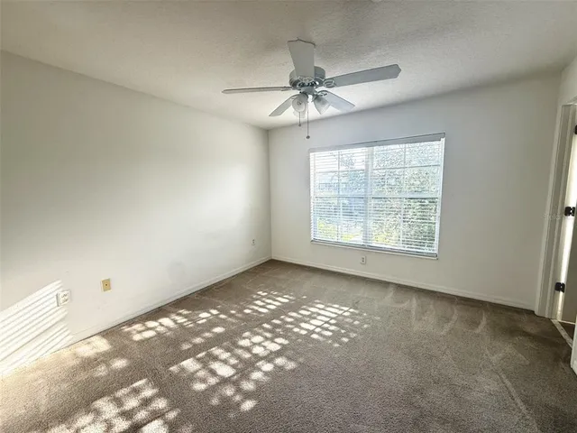 an empty room with windows and fan