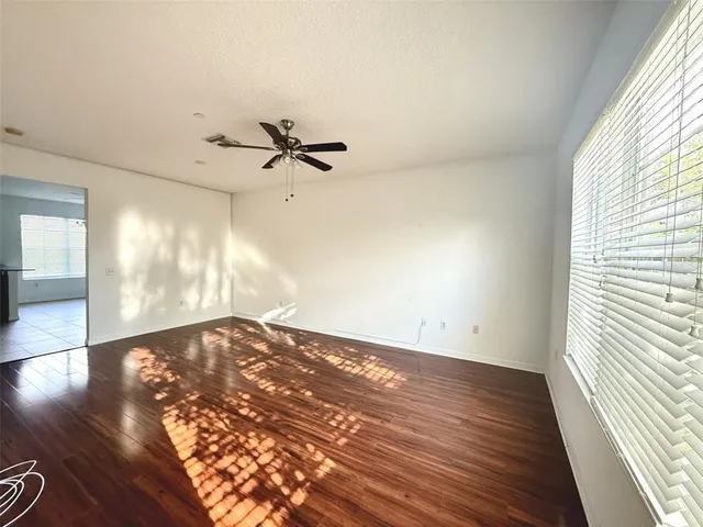 an empty room with wooden floor fan and windows