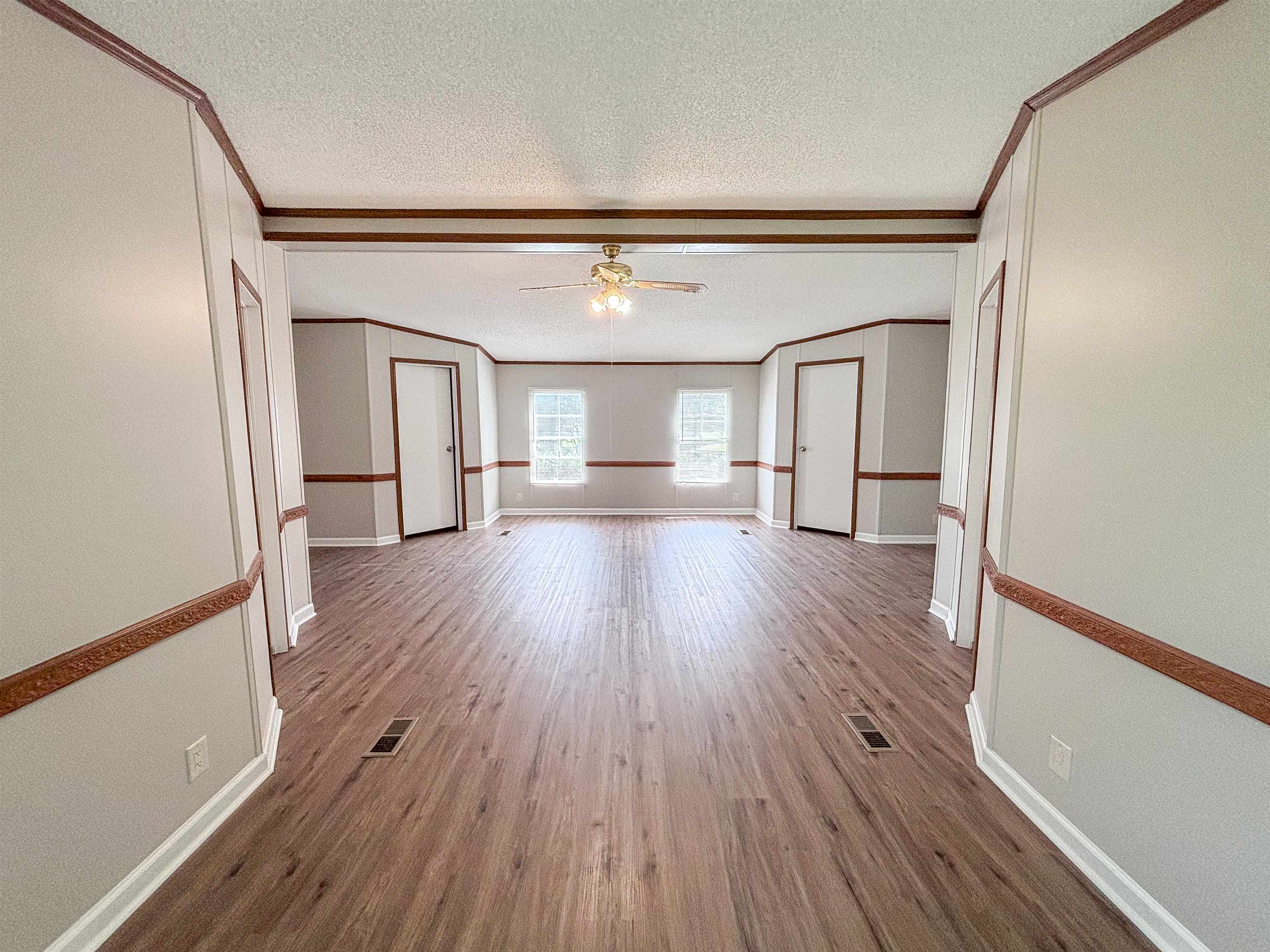2847 Holly Grove Road Covington, TN 38019 - Photo 17 of 36 Expansive open-concept room featuring wood-finish flooring, light gray walls with white trim, and decorative wood molding