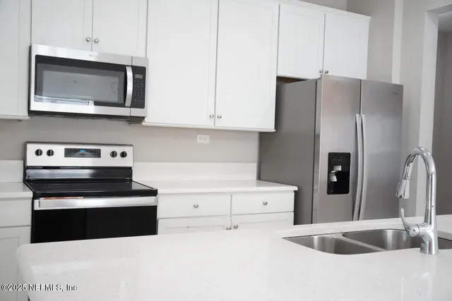 a kitchen with stainless steel appliances granite countertop a refrigerator a stove and a sink with wooden floor