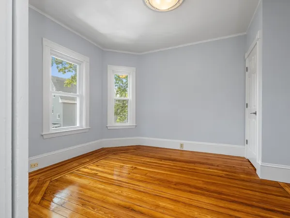 a view of empty room with window and wooden floor