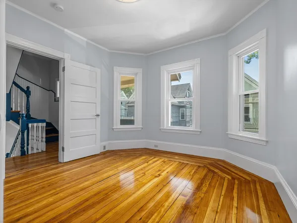 a view of empty room with window and wooden floor