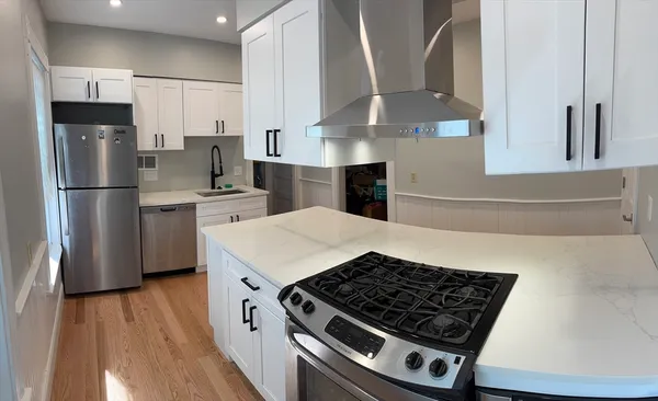 a kitchen with stainless steel appliances granite countertop a sink a stove a refrigerator and island with wooden floor