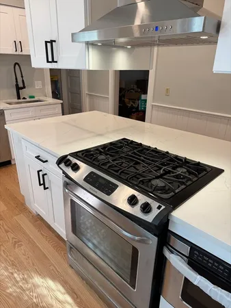 a stove sitting inside of a kitchen with stainless steel appliances wooden floor