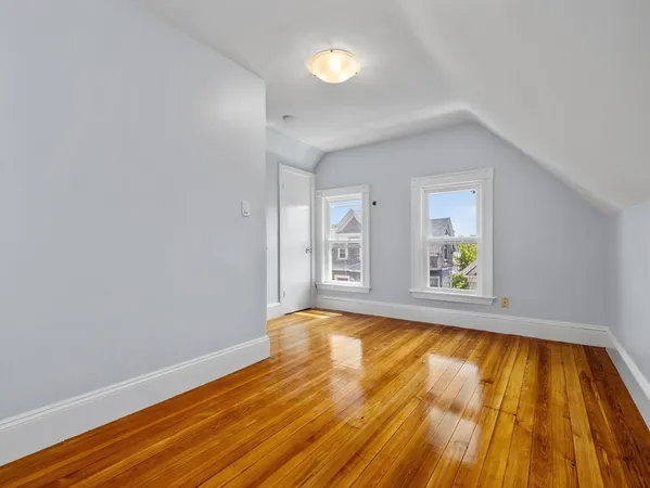 a view of an empty room with window and wooden floor