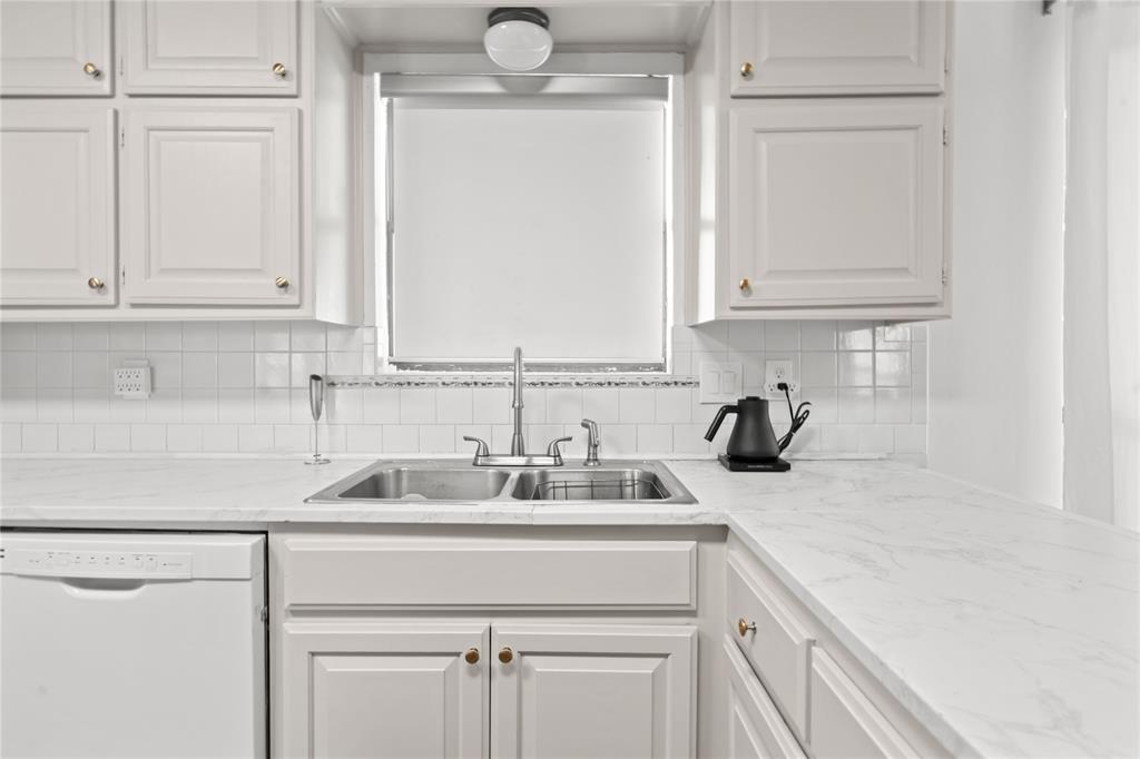 3506 Ruidoso Drive Arlington, TX 76017 - Photo 14 of 37 Kitchen featuring a double basin stainless steel sink, white paneled cabinetry with gold-tone hardware, white tile backsplash, and light-toned countertops