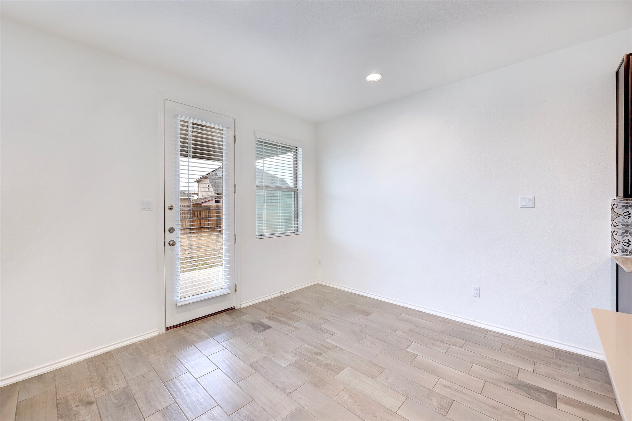307 Simmental Loop Hutto, TX 78634 - Photo 14 of 34 Natural light floods this versatile space, featuring durable wood-look tile flooring and direct outdoor access.
