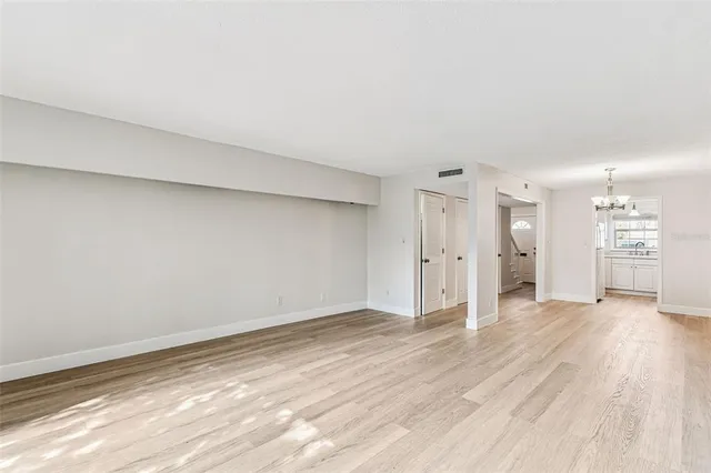 a view of an empty room with wooden floor kitchen and a window