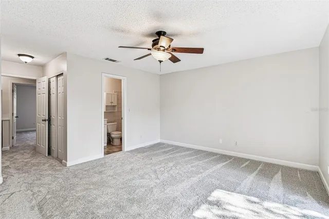 an empty room with closet and a ceiling fan