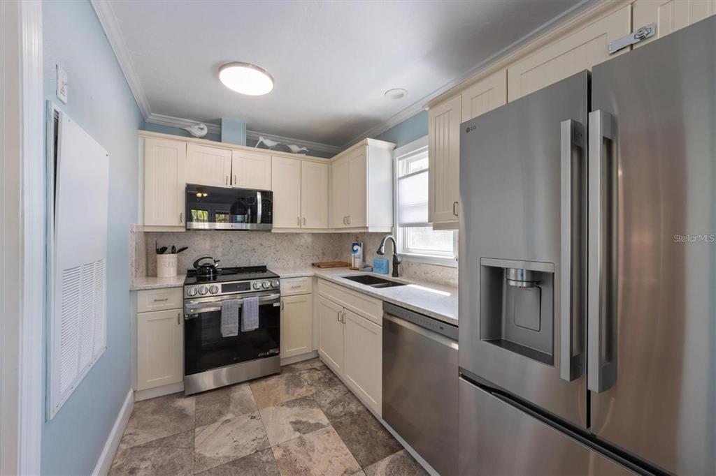 110 Oak Avenue, Unit A Anna Maria, FL 34216 - Photo 13 of 30 a kitchen with stainless steel appliances granite countertop a refrigerator a stove top oven a sink and dishwasher