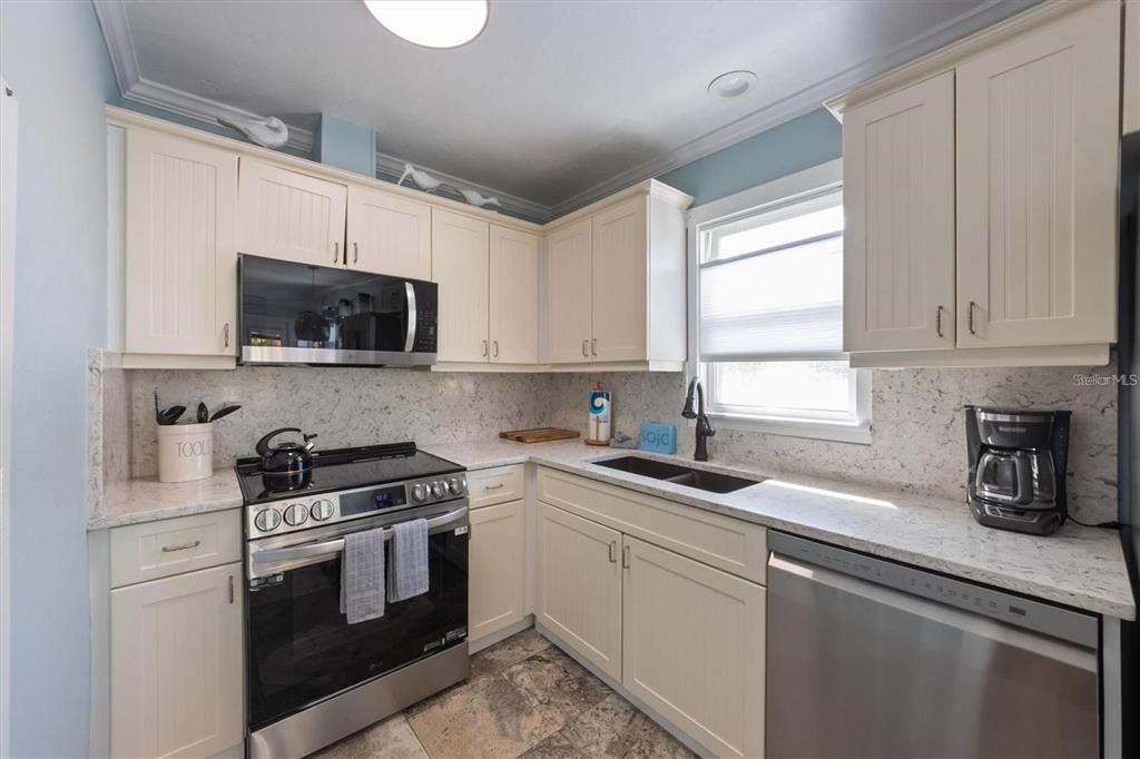 110 Oak Avenue, Unit A Anna Maria, FL 34216 - Photo 14 of 30 a kitchen with white cabinets stainless steel appliances and sink