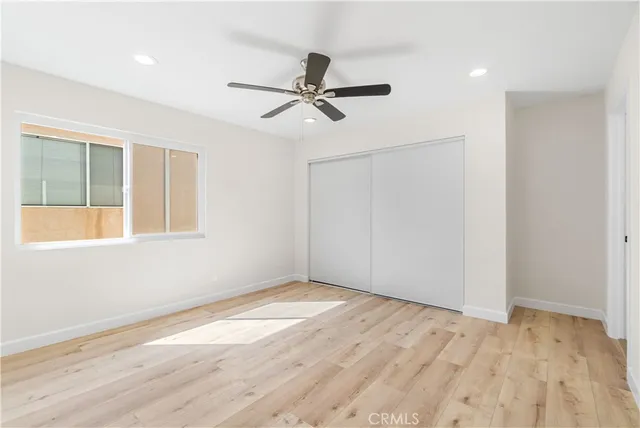a view of empty room with wooden floor and fan