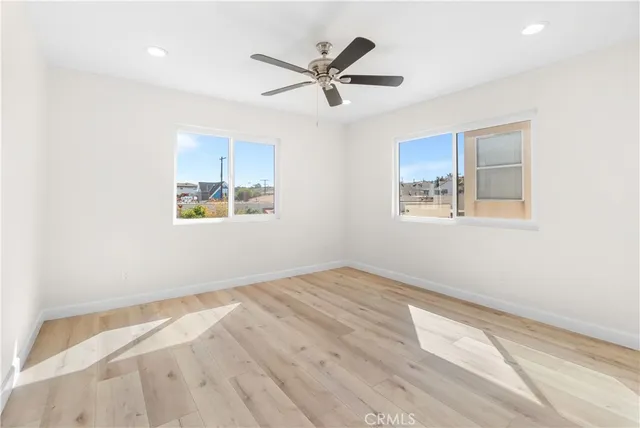 a view of empty room with wooden floor and ceiling fan