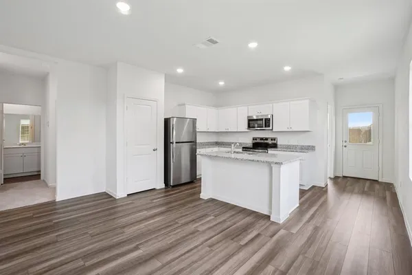 a kitchen with stainless steel appliances a refrigerator and wooden floor