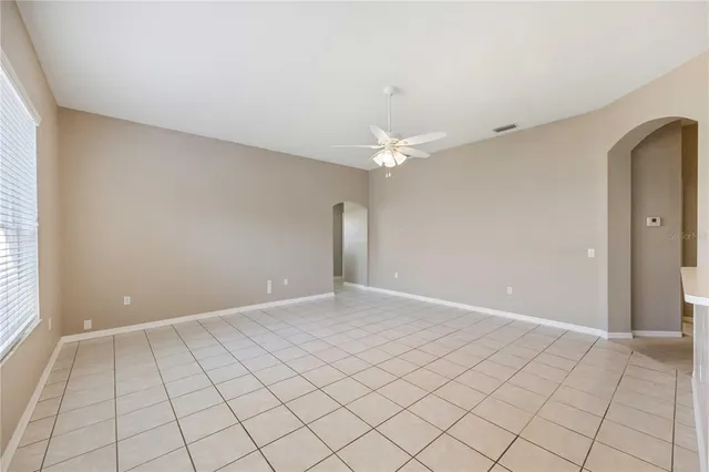 an empty room with chandelier fan and window