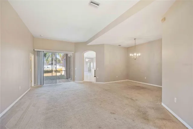 an empty room with windows and chandelier fan