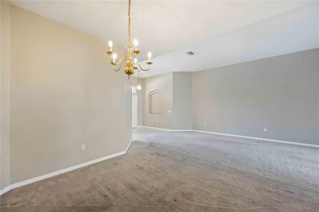 a view of an empty room with a chandelier fan