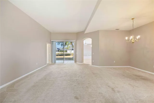 an empty room with a chandelier fan and windows