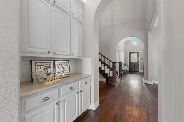 a hallway with white cabinets and wooden floor