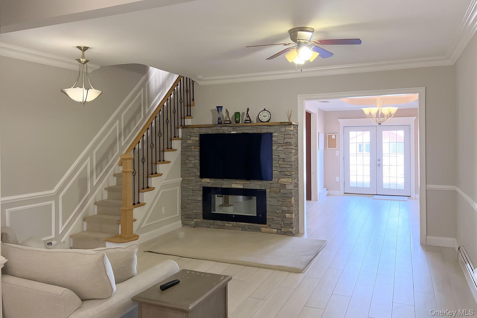67-31 52nd Road Queens, NY 11378 - Photo 2 of 21 Living room featuring crown molding, a fireplace, wood finished floors, french doors, and a baseboard heating unit