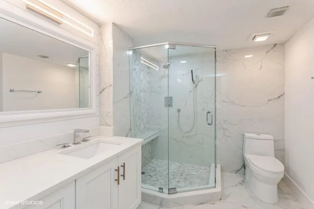 a bathroom with a shower sink vanity mirror and toilet