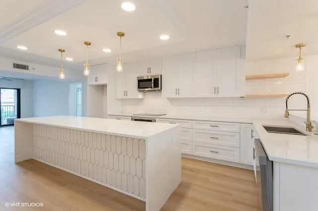 a kitchen with a sink a stove top oven and white cabinets