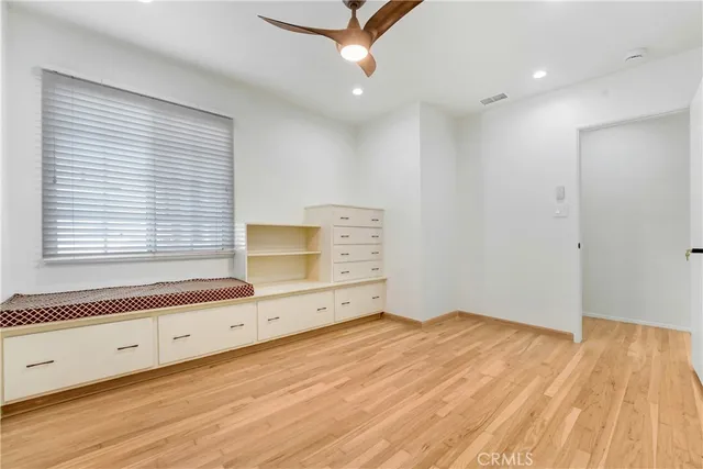 a view of empty room with wooden floor and fan
