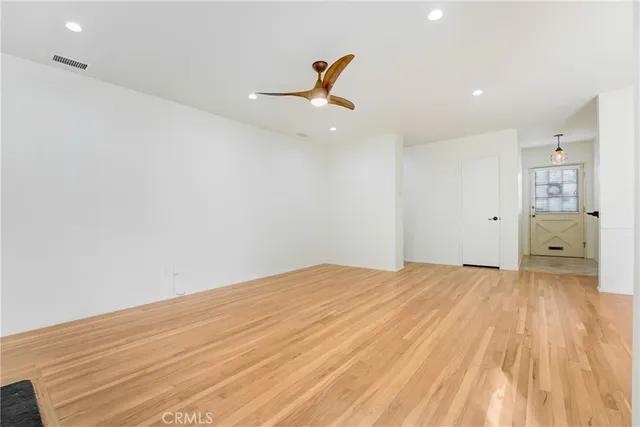 a view of empty room with wooden floor and ceiling fan