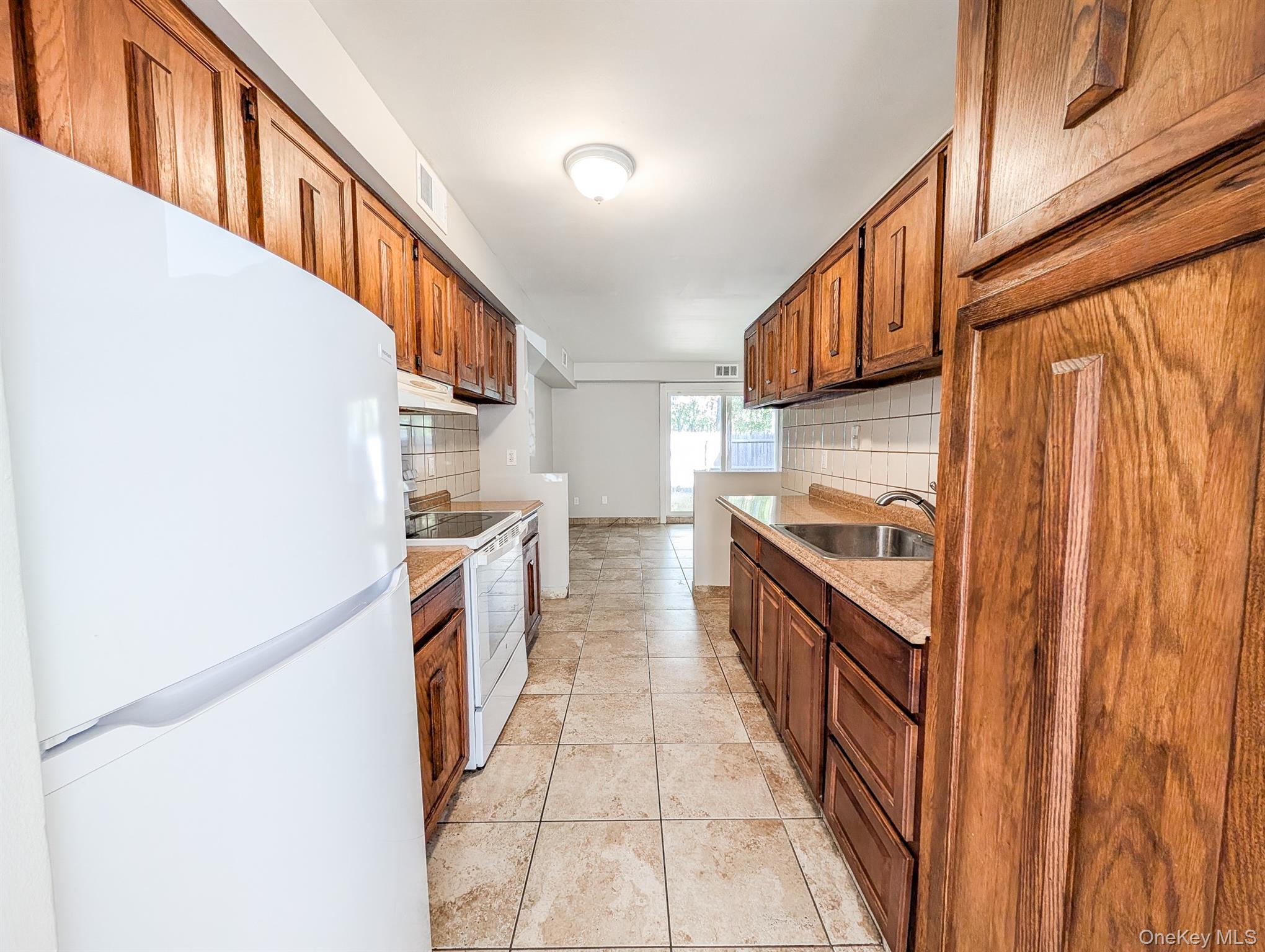 136 Hill Crescent Calverton, NY 11933 - Photo 3 of 21 Kitchen with white appliances, decorative backsplash, and brown cabinets