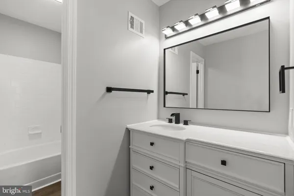 a bathroom with a sink vanity tub and a mirror